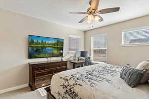 Carpeted bedroom with ceiling fan and a textured ceiling