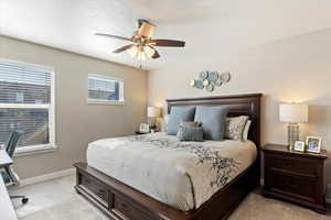 Carpeted bedroom featuring ceiling fan and a textured ceiling