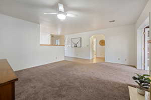 Unfurnished living room featuring carpet, a textured ceiling, and ceiling fan