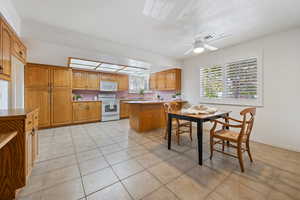 Kitchen with light tile patterned floors, white appliances, ceiling fan, a textured ceiling, and kitchen peninsula