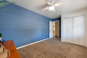 Unfurnished bedroom featuring ceiling fan, carpet flooring, a closet, and a textured ceiling