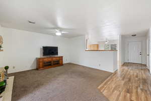 Unfurnished living room with a textured ceiling, ceiling fan, and carpet