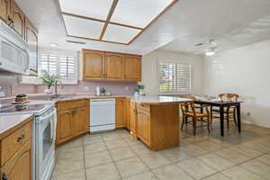 Kitchen featuring plenty of natural light, sink, white appliances, and kitchen peninsula