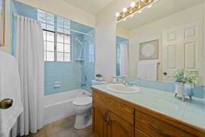 Full bathroom with vanity, shower / tub combo, tile patterned floors, and toilet