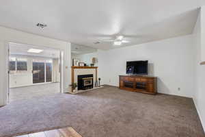 Carpeted living room with ceiling fan and a textured ceiling