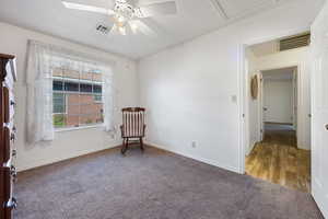 Living area with a textured ceiling, ceiling fan, and dark colored carpet