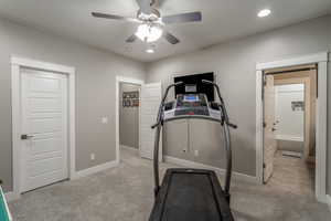 Exercise room with light carpet and ceiling fan