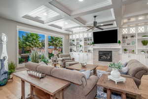 Living room with coffered ceiling, built in features, ceiling fan, and light hardwood / wood-style flooring