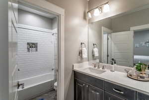 Full bathroom featuring tiled shower / bath, vanity, and toilet