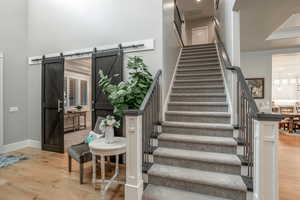 Stairway with a high ceiling, a barn door, and hardwood / wood-style floors