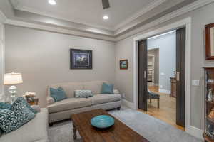 Living room with ornamental molding, ceiling fan, and light hardwood / wood-style flooring