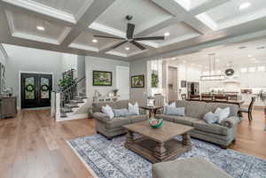 Living room with beamed ceiling, ornamental molding, coffered ceiling, and light wood-type flooring