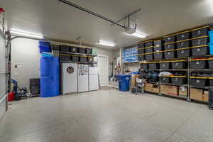 Garage featuring a garage door opener and white fridge