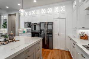 Kitchen with pendant lighting, stainless steel fridge with ice dispenser, and white cabinets