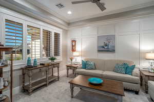 Carpeted living room featuring ceiling fan and ornamental molding