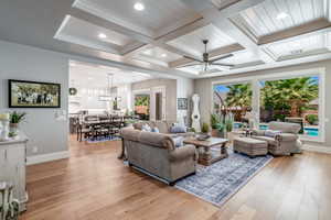 Living room featuring beamed ceiling, ceiling fan, coffered ceiling, and light wood-type flooring