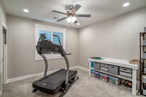 Exercise room with light carpet and ceiling fan