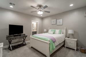 Carpeted bedroom with connected bathroom and ceiling fan