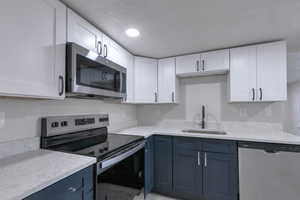 Kitchen featuring white cabinetry, appliances with stainless steel finishes, sink, and blue cabinetry