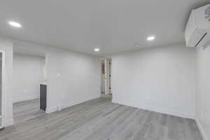 Empty room with light hardwood / wood-style floors and an AC wall unit