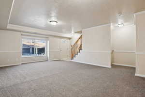 Unfurnished living room featuring a textured ceiling, ornamental molding, and carpet flooring