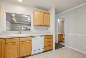 Kitchen with sink, light brown cabinets, dishwasher, and ornamental molding