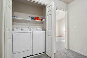 Laundry area featuring washer and clothes dryer and light colored carpet