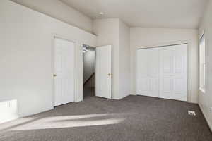 Unfurnished bedroom with a closet, vaulted ceiling, and carpet