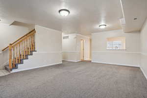 Carpeted spare room with a textured ceiling and ornamental molding