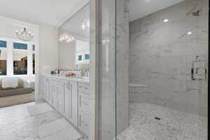 Bathroom with an inviting chandelier, tiled shower, and vanity