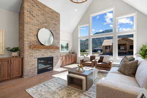 Living room with a mountain view, high vaulted ceiling, a brick fireplace, and light wood-type flooring