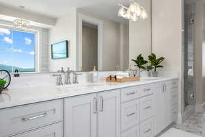 Bathroom with vanity, a notable chandelier, and a shower with door