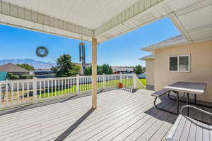 Wooden terrace featuring a mountain view and a yard