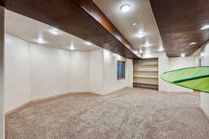 Basement with carpet flooring and a textured ceiling