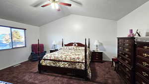 Bedroom with dark colored carpet, vaulted ceiling, ceiling fan, and a textured ceiling