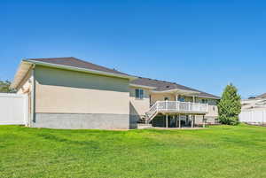 Rear view of house with a wooden deck and a yard