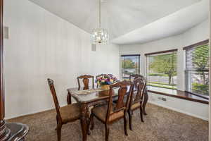 Dining space with carpet flooring and a notable chandelier