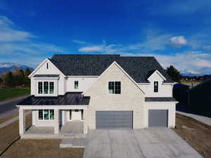Modern farmhouse with a standing seam roof, metal roof, an attached garage, driveway, and a mountain view