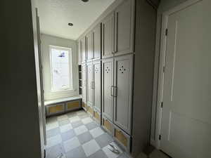 Mudroom featuring a textured ceiling and light floors