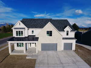 Modern farmhouse style home featuring metal roof, an attached garage, concrete driveway, a standing seam roof, and a mountain view