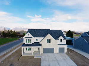 Modern farmhouse featuring metal roof, an attached garage, a standing seam roof, driveway, and a mountain view
