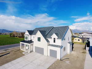 View of side of home featuring an attached garage, a standing seam roof, concrete driveway, and a mountain view