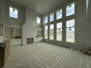 Unfurnished living room featuring a high ceiling and built in features