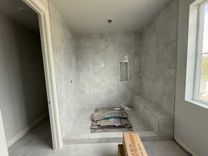 Full bathroom featuring baseboards, a tile shower, and tile patterned floors