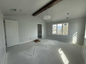 Unfurnished bedroom featuring baseboards, vaulted ceiling with beams, and visible vents