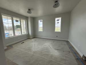 Spare room featuring baseboards, a textured ceiling, and concrete flooring