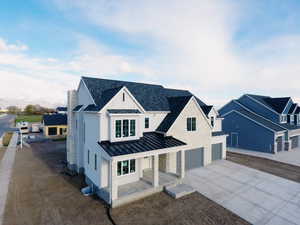 Modern inspired farmhouse with driveway, a standing seam roof, stone siding, an attached garage, and metal roof