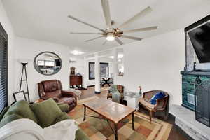 Living room featuring ceiling fan, a wall mounted air conditioner, and a tiled fireplace