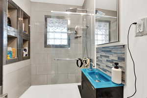 Bathroom with vanity, backsplash, and walk in shower