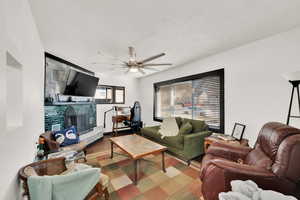 Living room with wood-type flooring, a fireplace, and ceiling fan